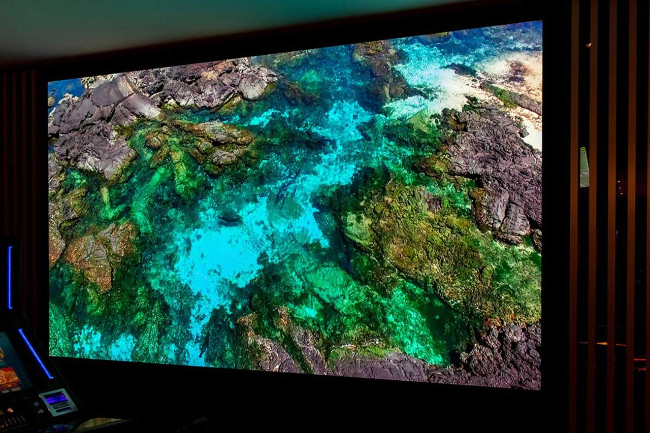 Digital wall at Club Central Hurstville showing a rocky coastline and turquoise water.