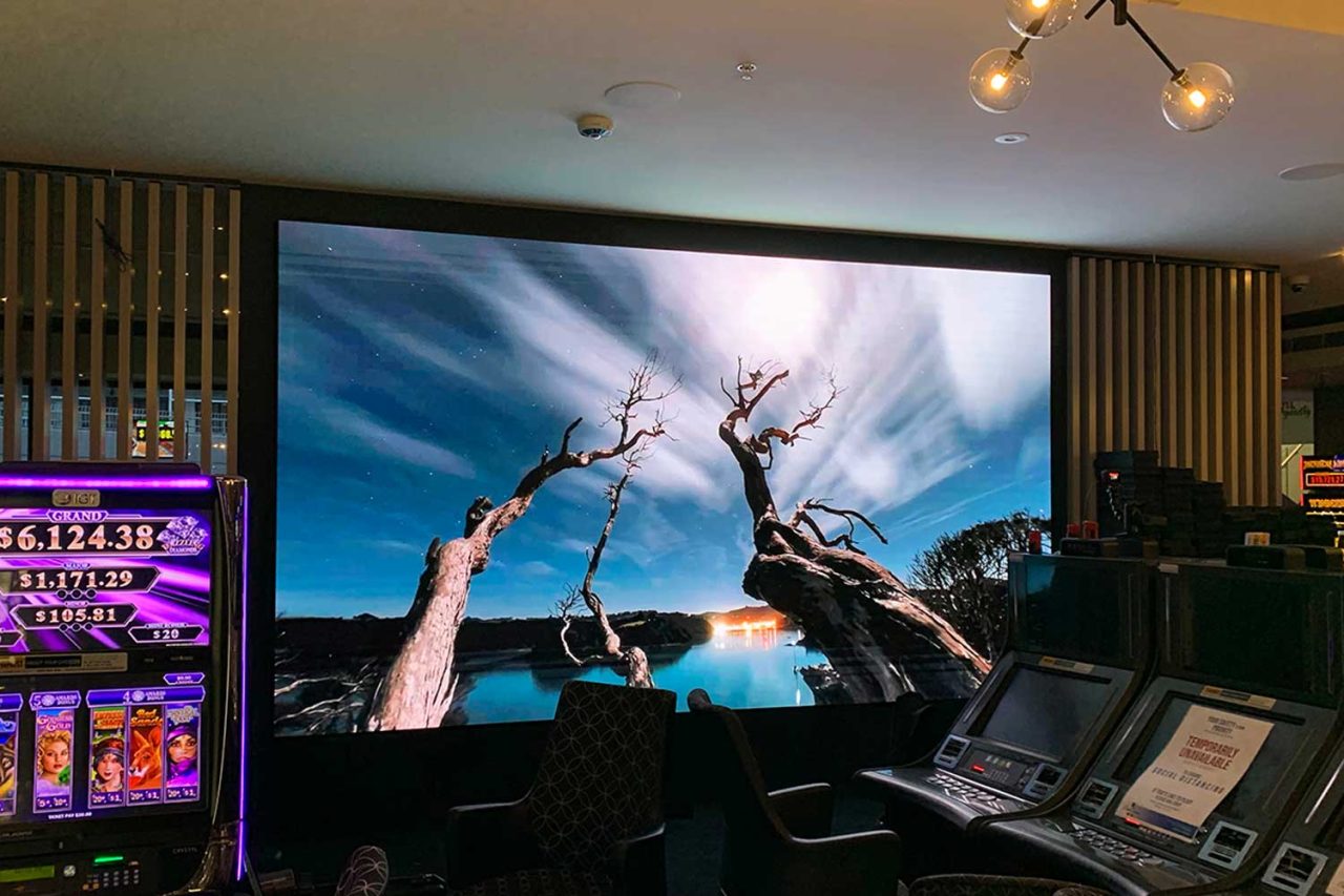 Digital wall in the Club Central Hurstville gaming lounge showing a tree beneath a dramatic sky.