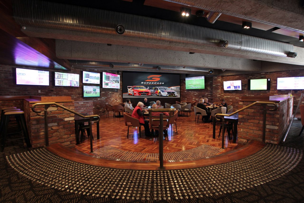 Wide view of the 1st on Wharf Tavern sports lounge, with screens around its seating area.