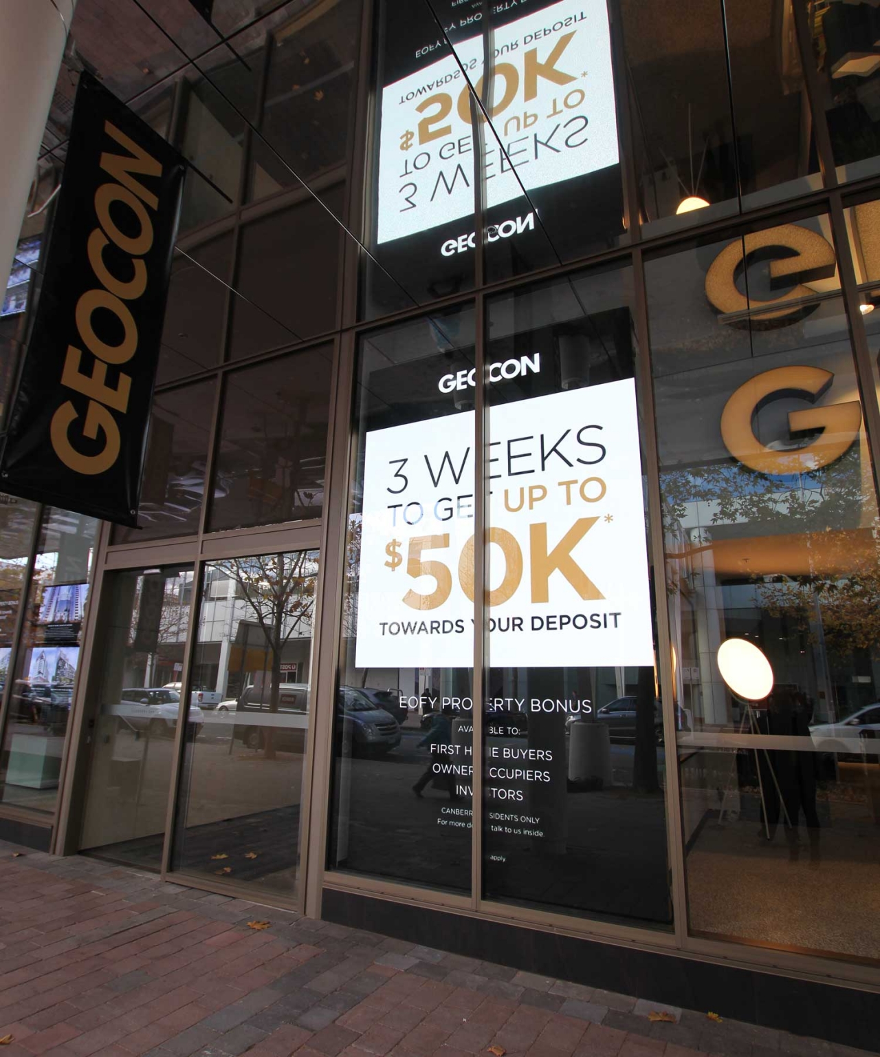 Angled view of vertical digital advertisements behind Geocon's glass frontage.
