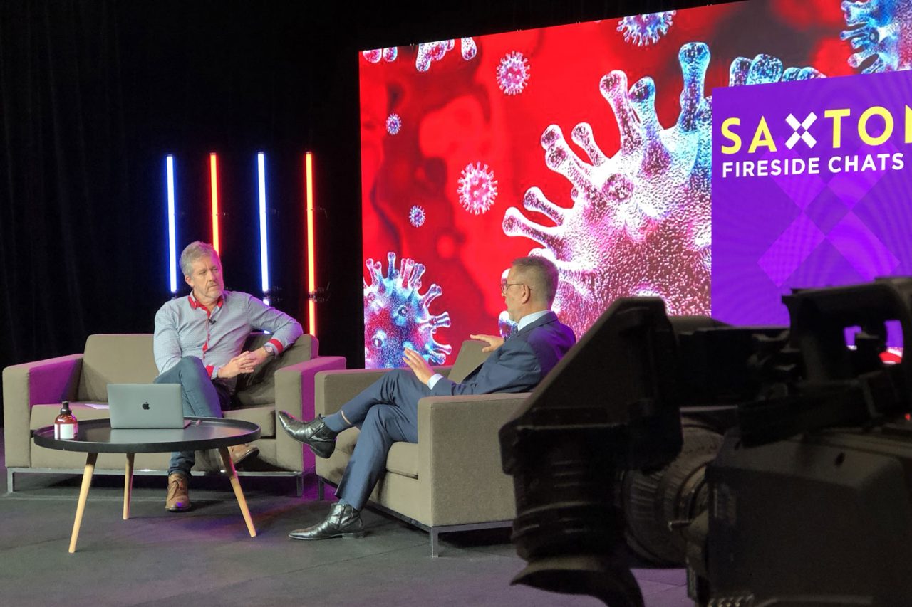 Two speakers seated for a fireside chat in a Scene Change virtual studio with a colourful digital backdrop.