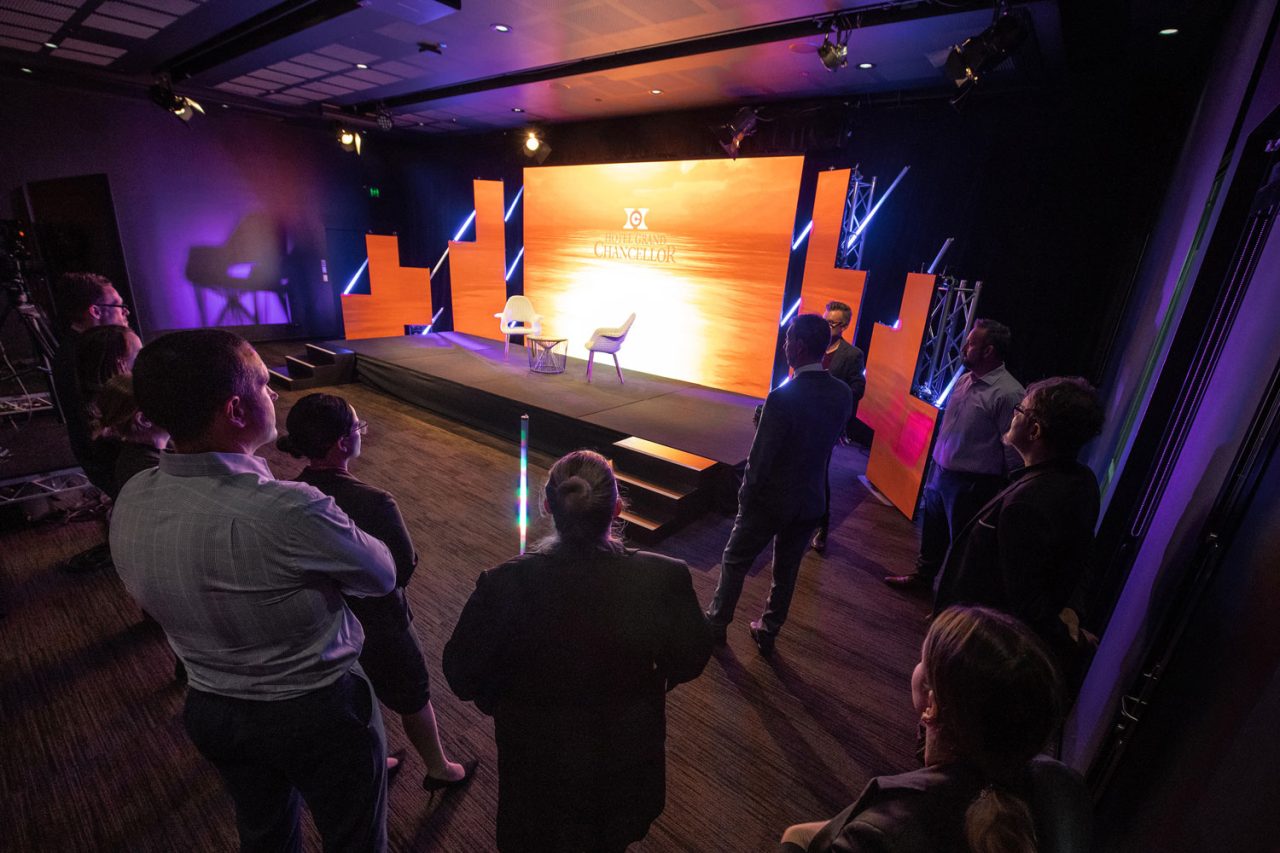 Production crew facing a brightly lit presentation stage in a Scene Change virtual studio.