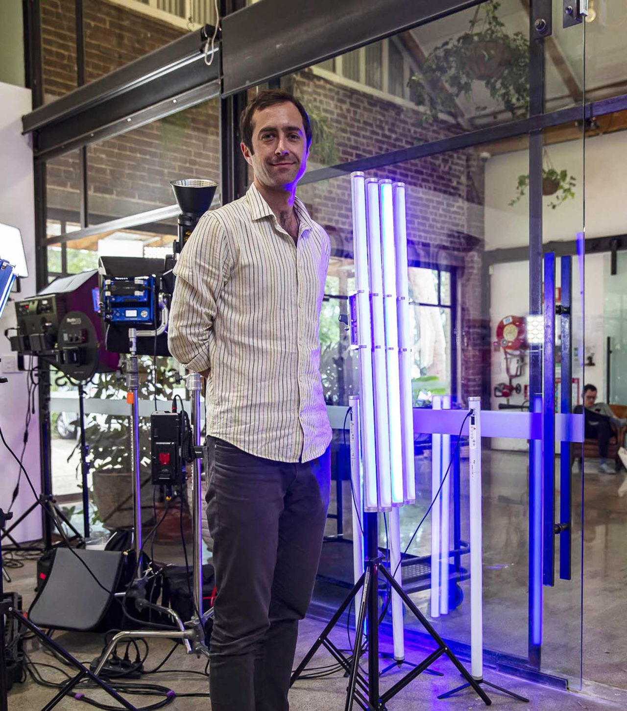 A Sunstudios team member beside upright purple and white light tubes.