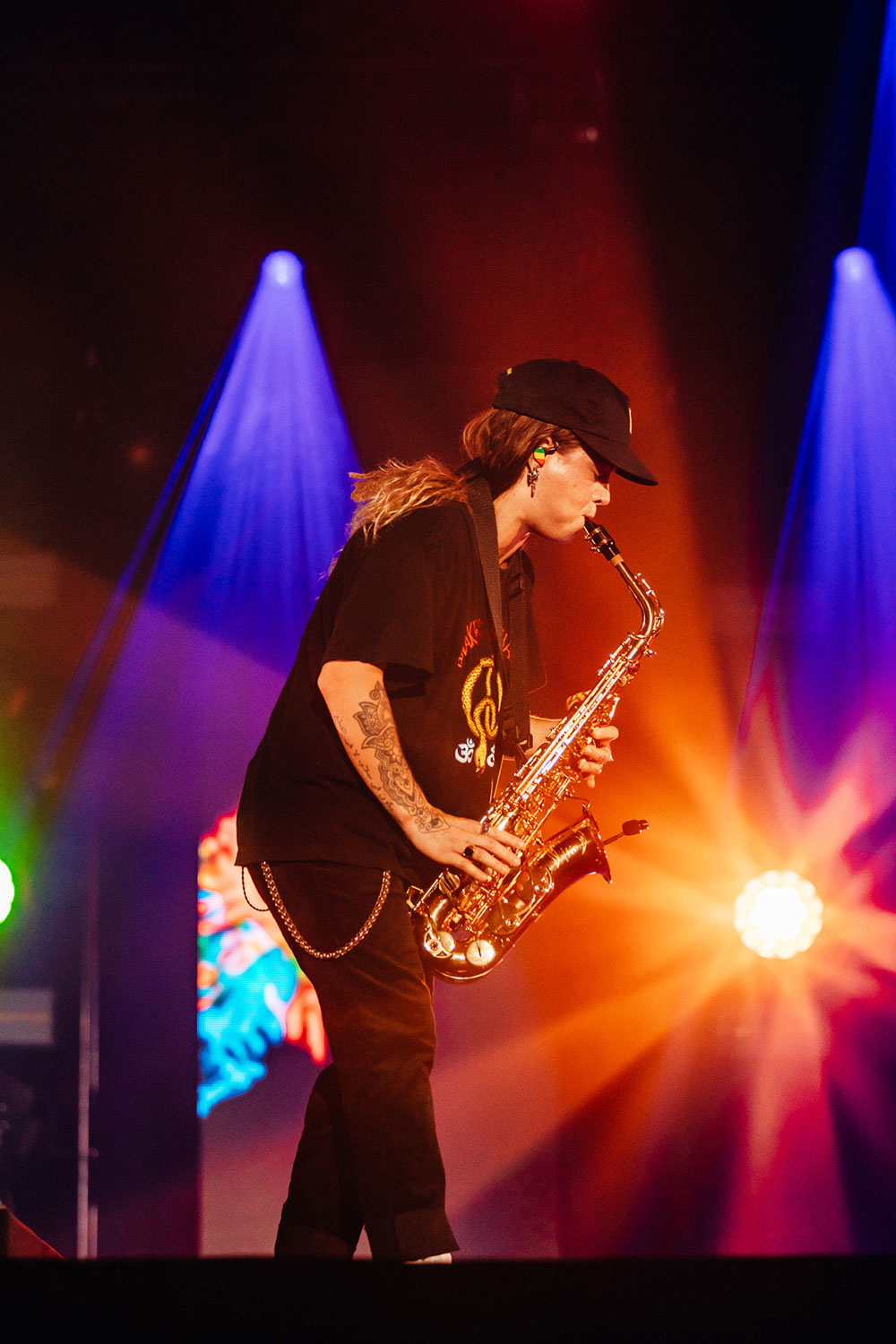 Tash Sultana playing saxophone under warm stage lighting at Great Southern Nights.