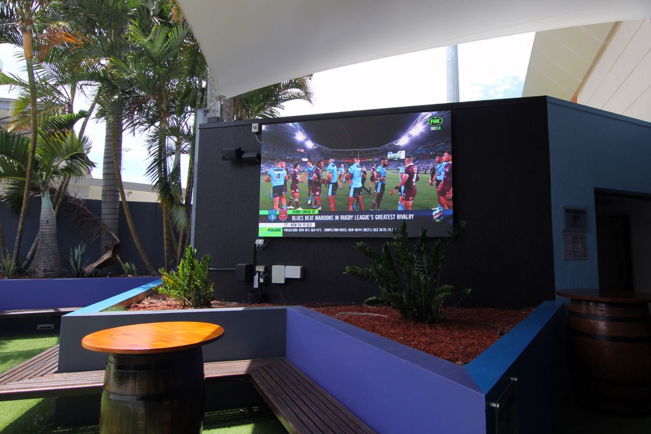 Outdoor screen showing sport above the blue seating at Redcliffe Leagues Club.
