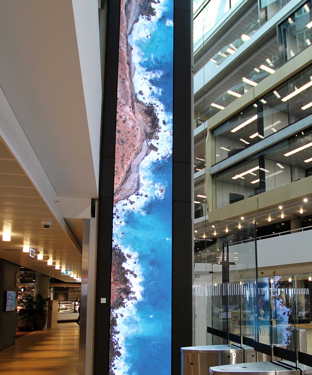 Tall digital LED column displaying blue imagery beside the lift shaft in a Sydney corporate headquarters.
