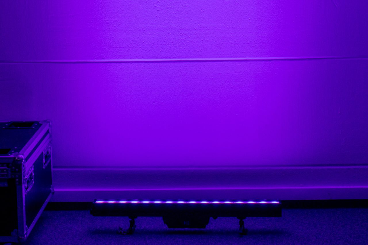 Purple light washes a wall above an Astera AX2 PixelBar.