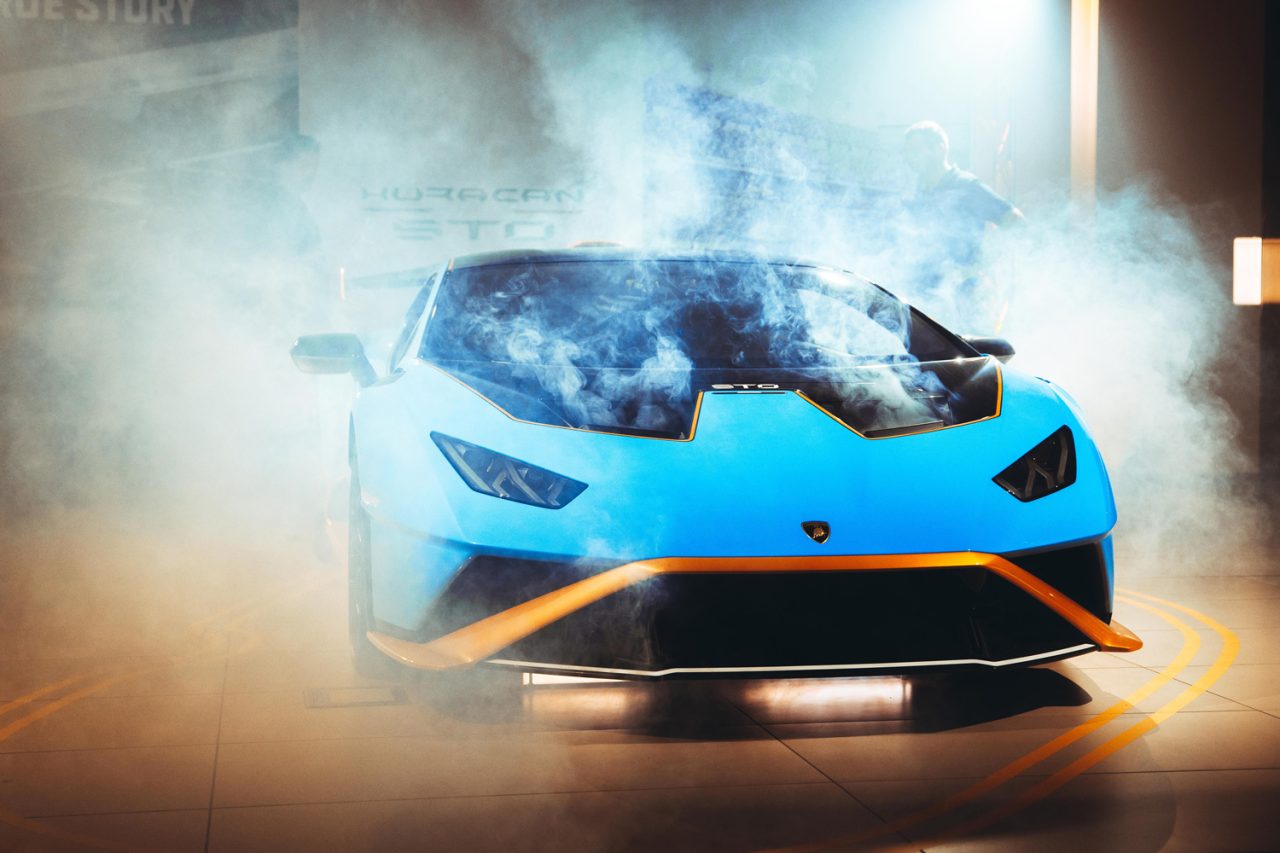 Blue Lamborghini Huracan STO emerging through haze at the launch event.