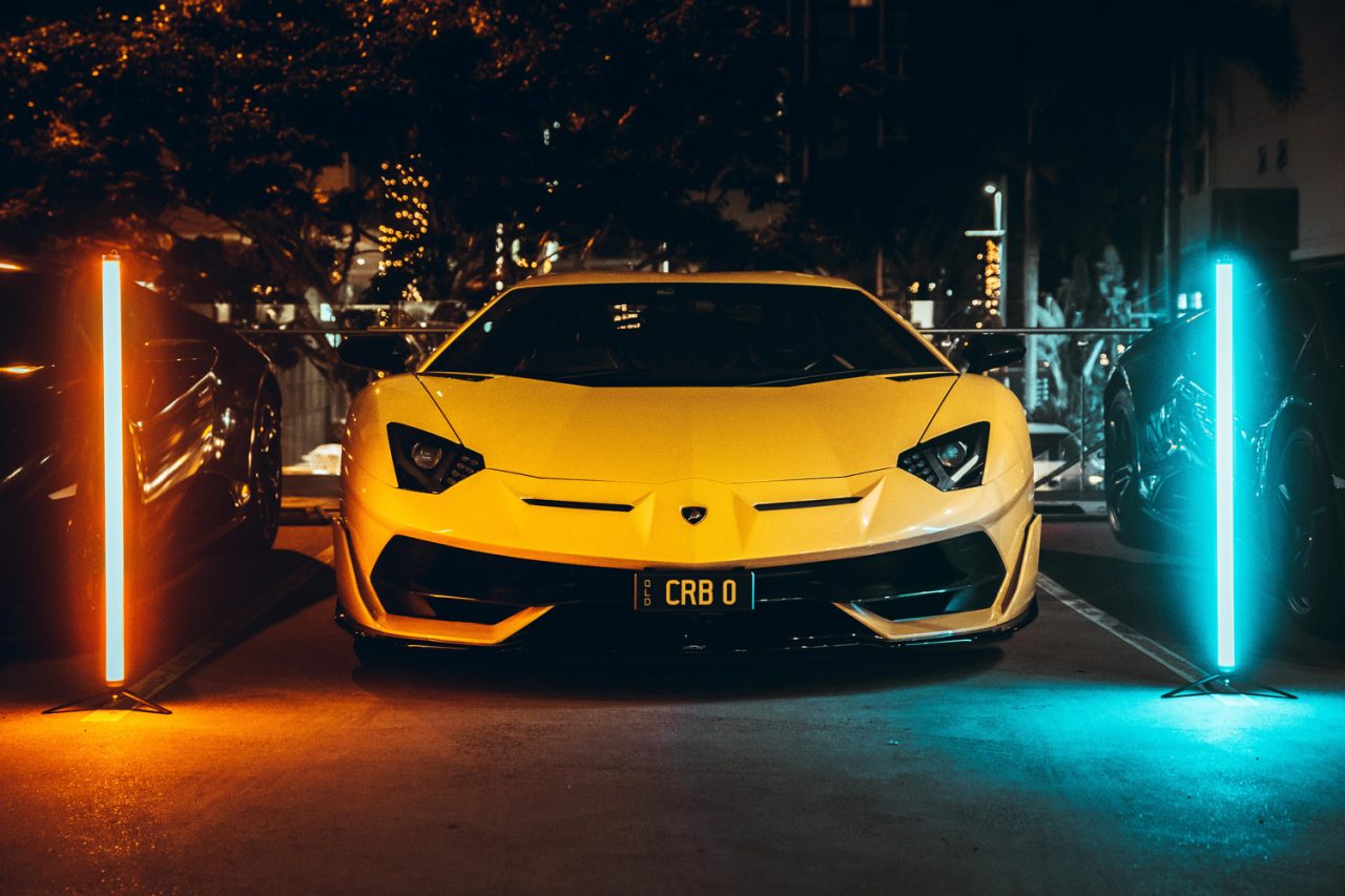 Yellow Lamborghini between orange and cyan light tubes at the launch event.