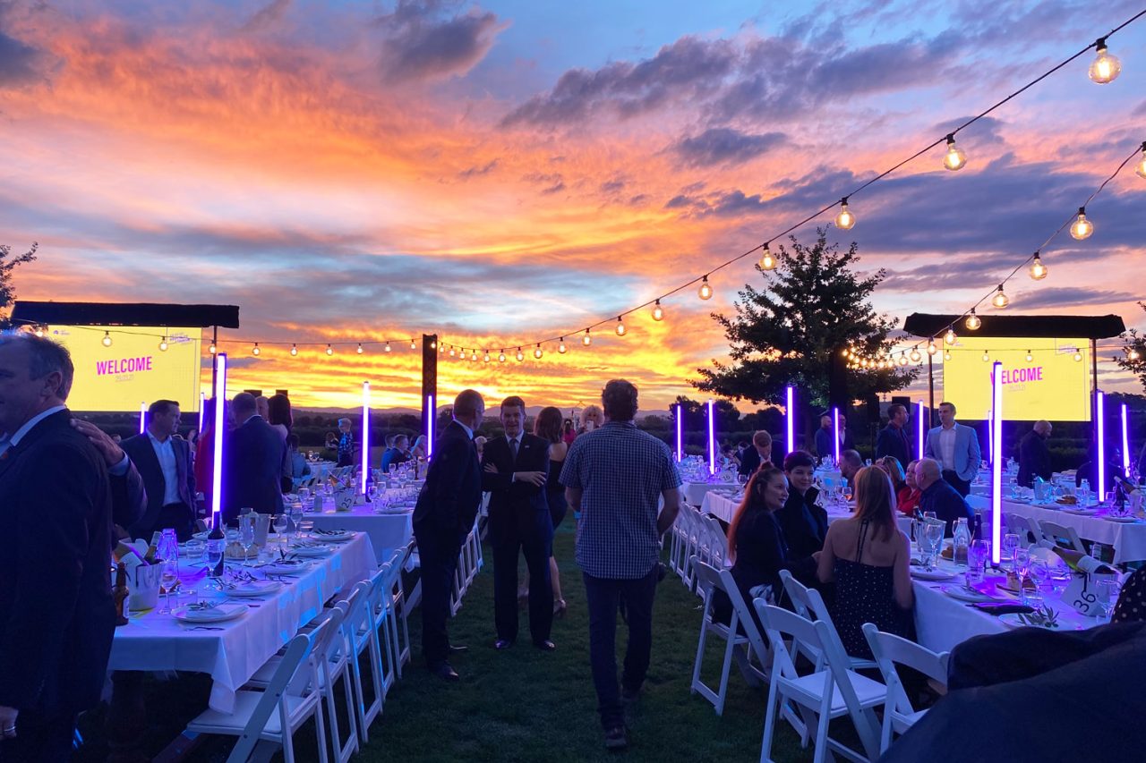 Outdoor AHA Awards dinner in Canberra with purple light tubes between the tables at dusk.