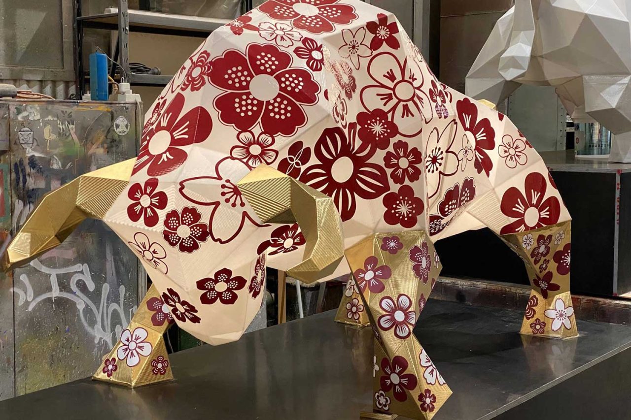 White ox sculpture decorated with red floral patterns, photographed indoors before illumination.