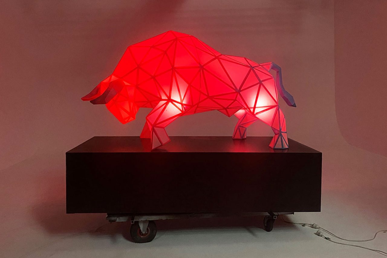 Faceted ox sculpture illuminated red on a black plinth for Chinese New Year in Darling Harbour.