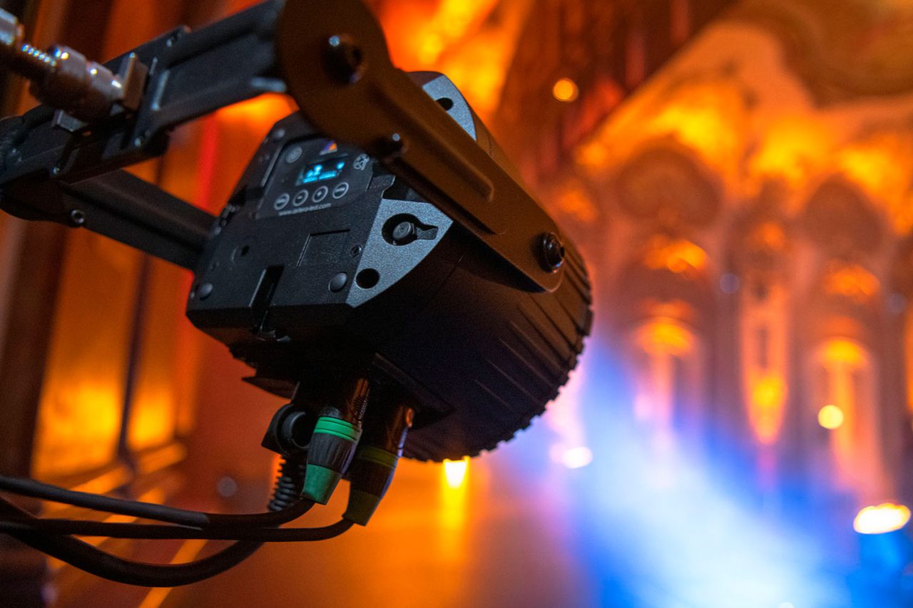 Astera AX9 PowerPAR mounted overhead amid coloured lighting.