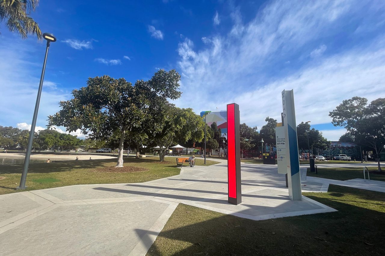 Red digital column beside a white signpost in the paved plaza at HOTA.
