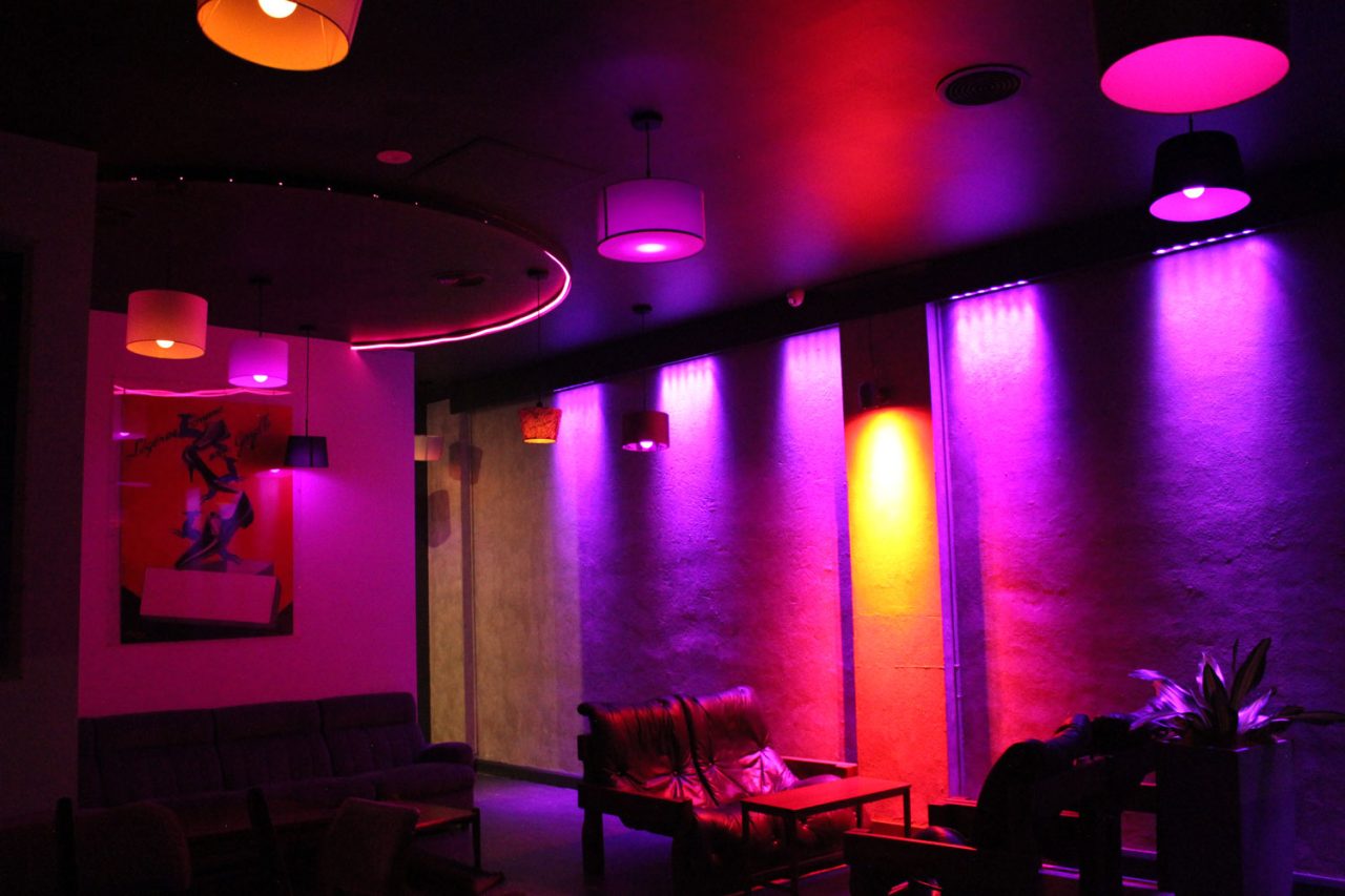 Purple and yellow accent lighting around the lounge beneath multicoloured pendants at One22.