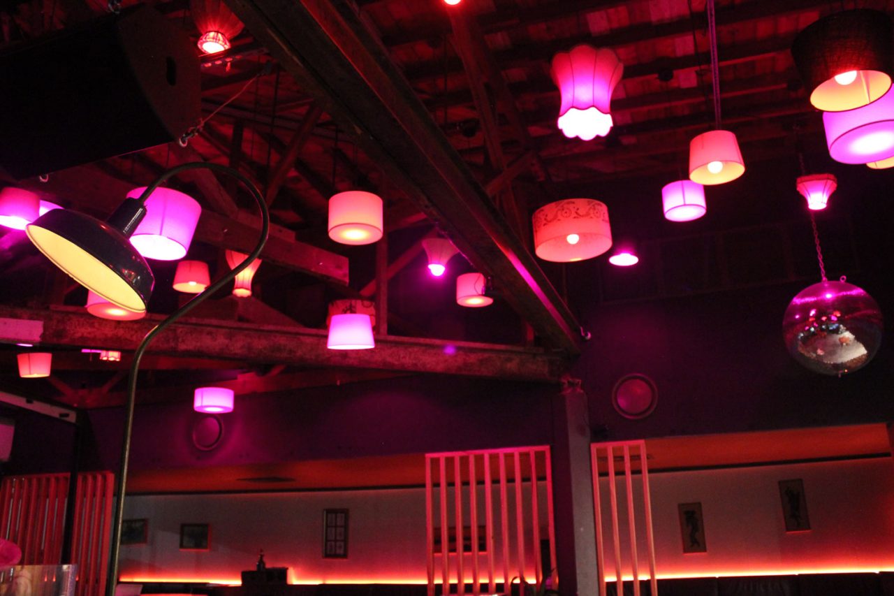 Pink and red pendant lighting across the exposed ceiling at One22 bar in Canberra.