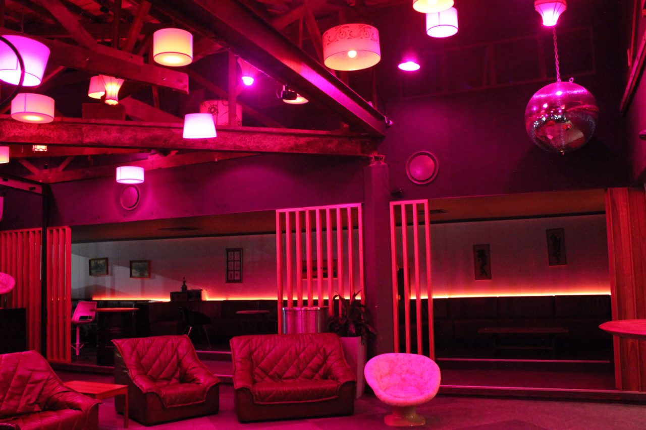 Bar seating and pendant lights illuminated red and pink at One22 in Canberra.