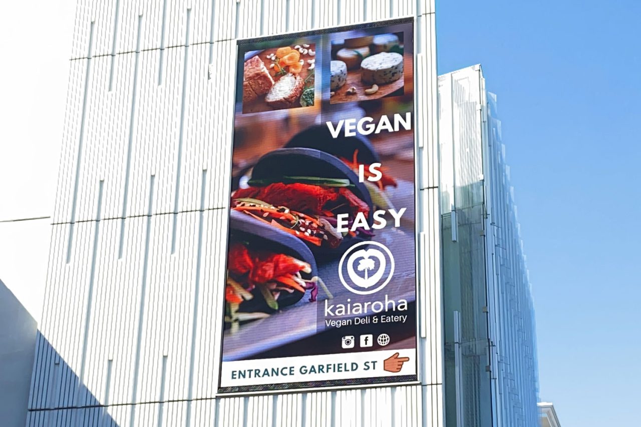 A vegan food advertisement on the vertical facade screen at 100 Parnell Road.