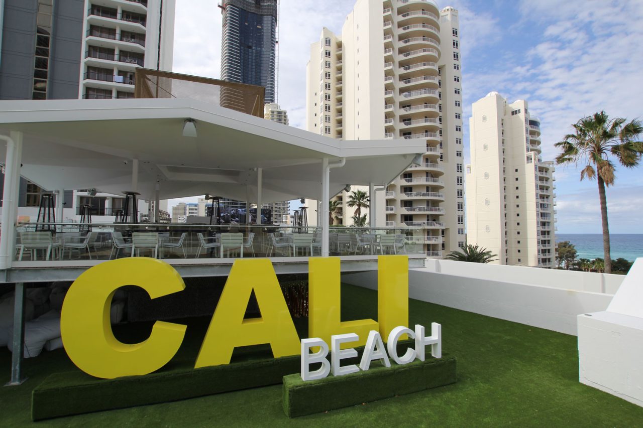 Large yellow Cali Beach sign beside the rooftop venue.