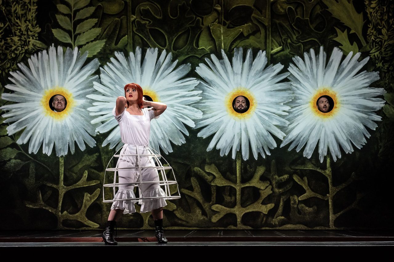 Performer in front of large daisy scenery in a Royal Opera House production.
