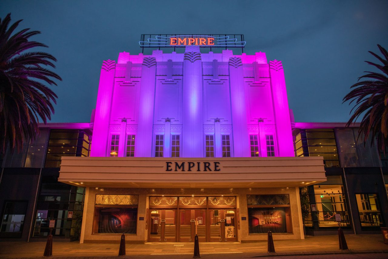 Magenta lighting across the Empire Theatre facade at dusk.