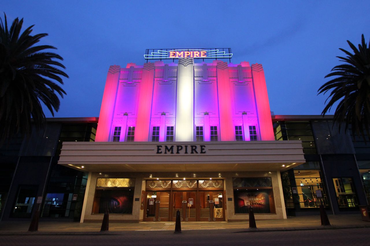 The Empire Theatre facade illuminated pink and purple at dusk.