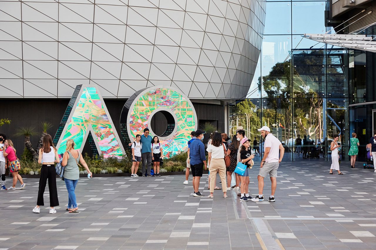 Visitors gather around the patterned AO digital sign outside the arena.