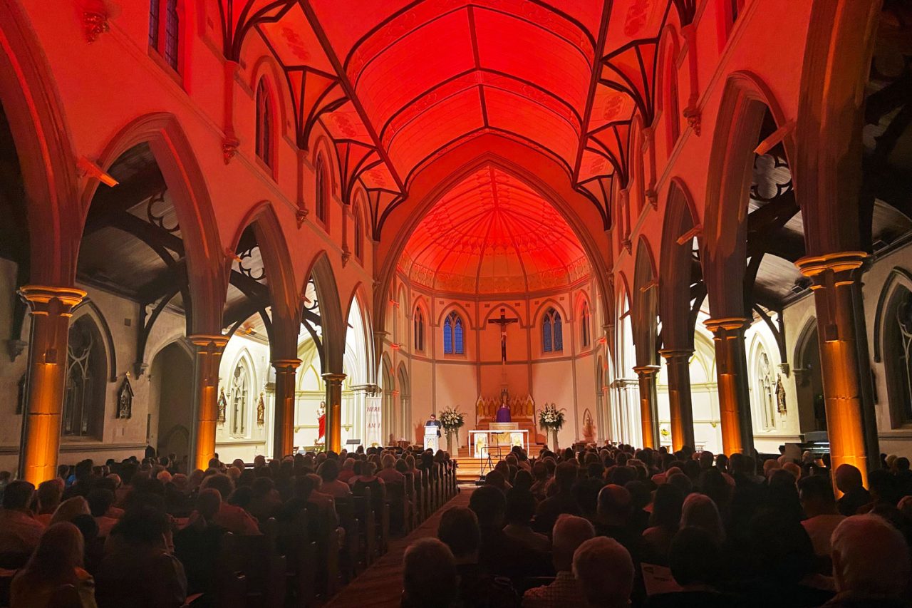 Red lighting across the vaulted ceiling at St Joseph's Church during the concert.