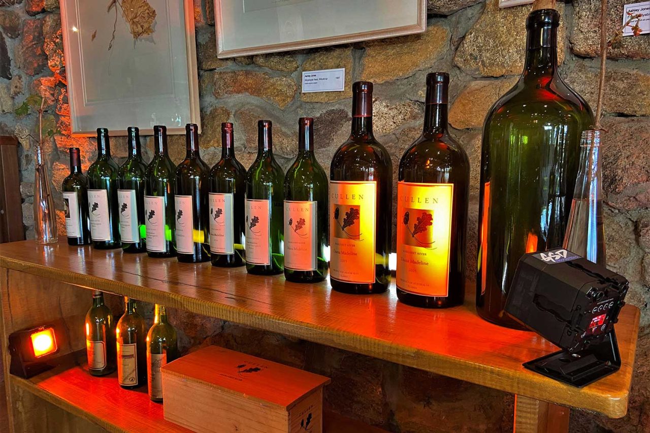 Wine bottles illuminated from below on a Cullen Wines display shelf.