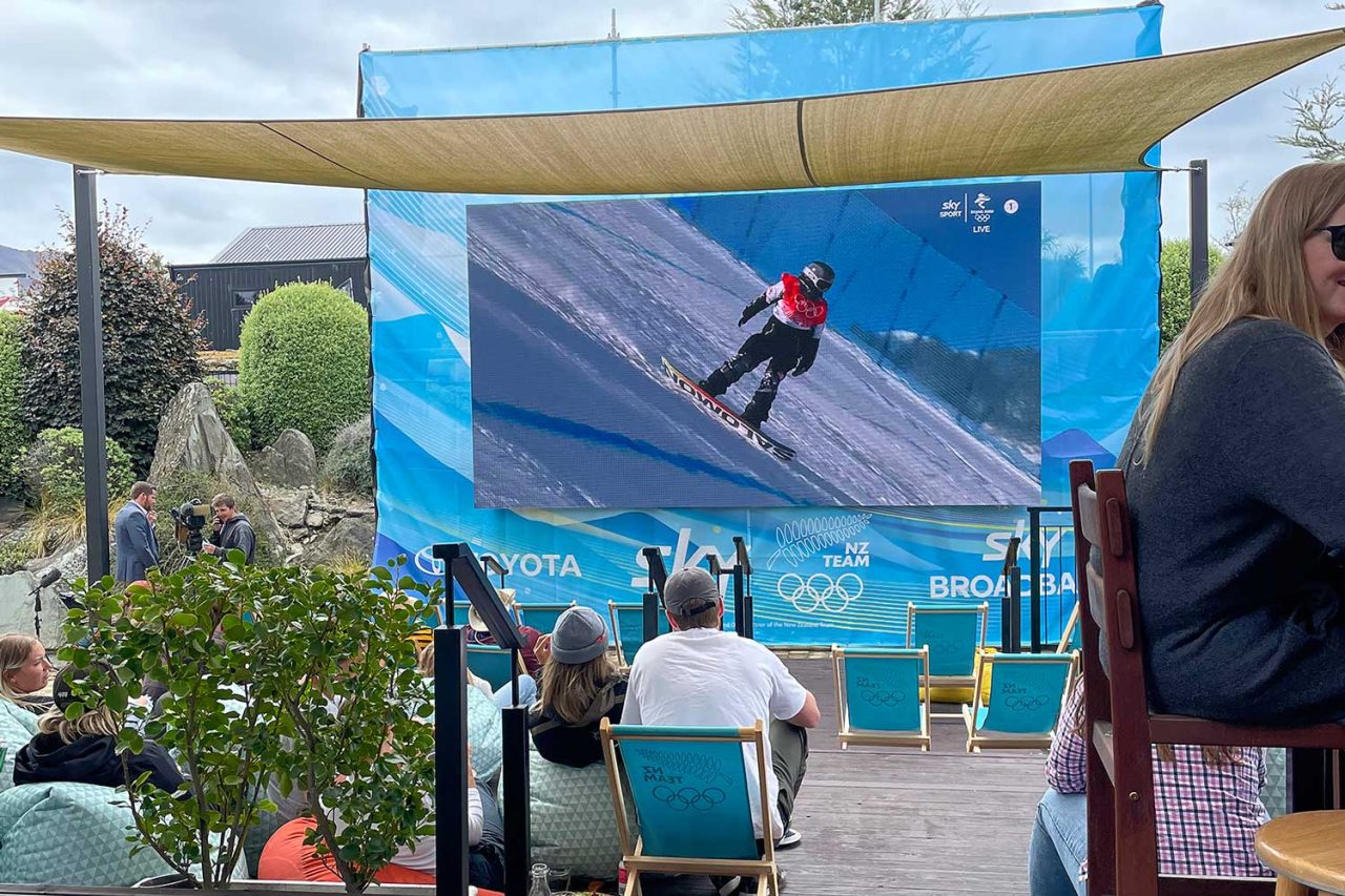 Outdoor screen shows winter sports footage above spectators at a TomTom Productions event.