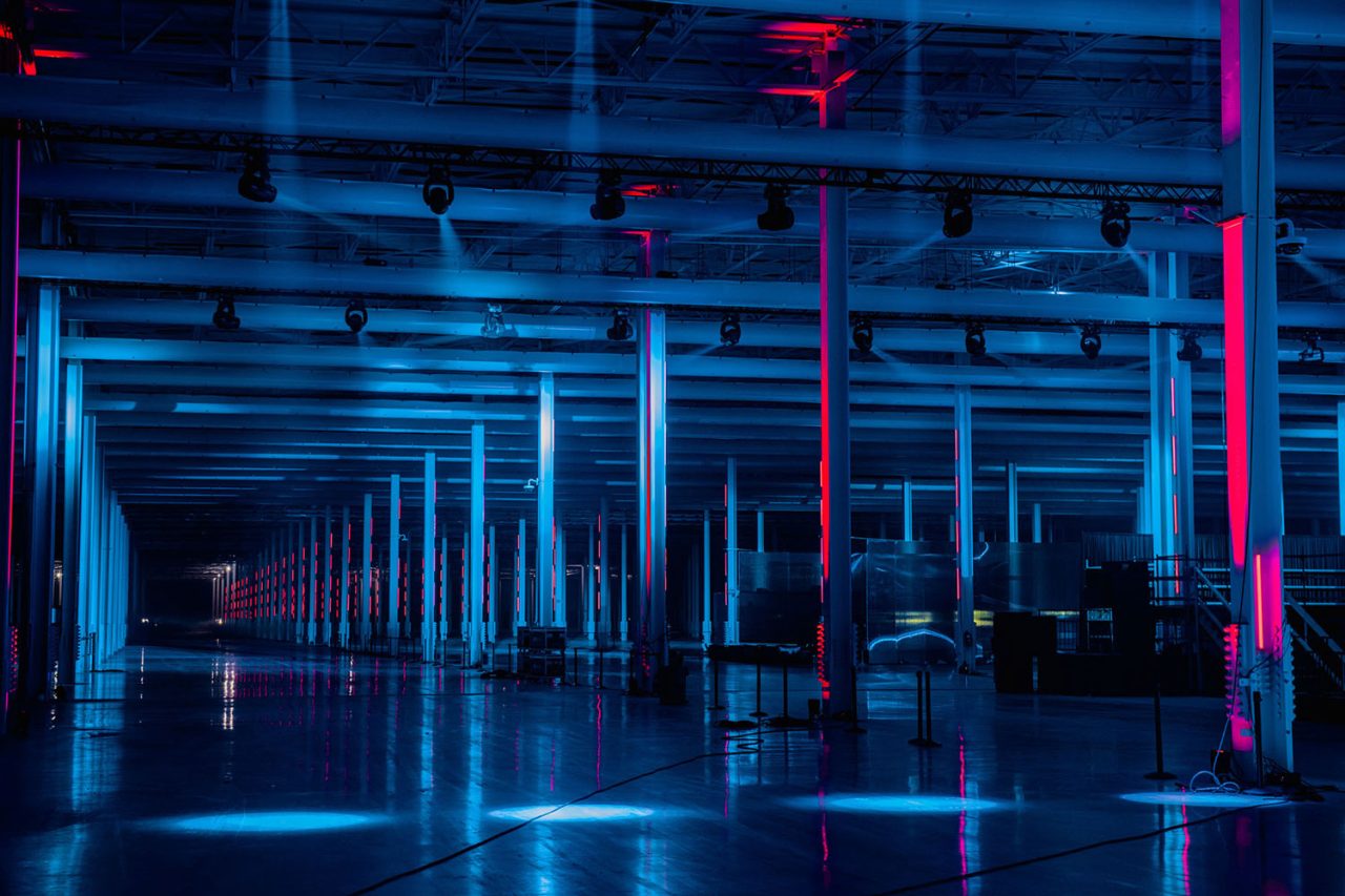Blue and pink lighting along the Gigafactory aisle at Cyber Rodeo.