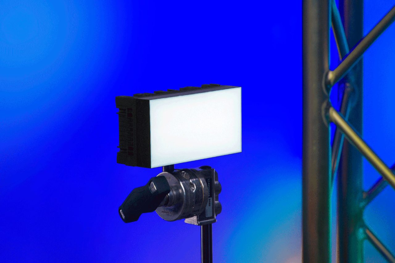 Astera HydraPanel emitting white light on a stand against a blue background.
