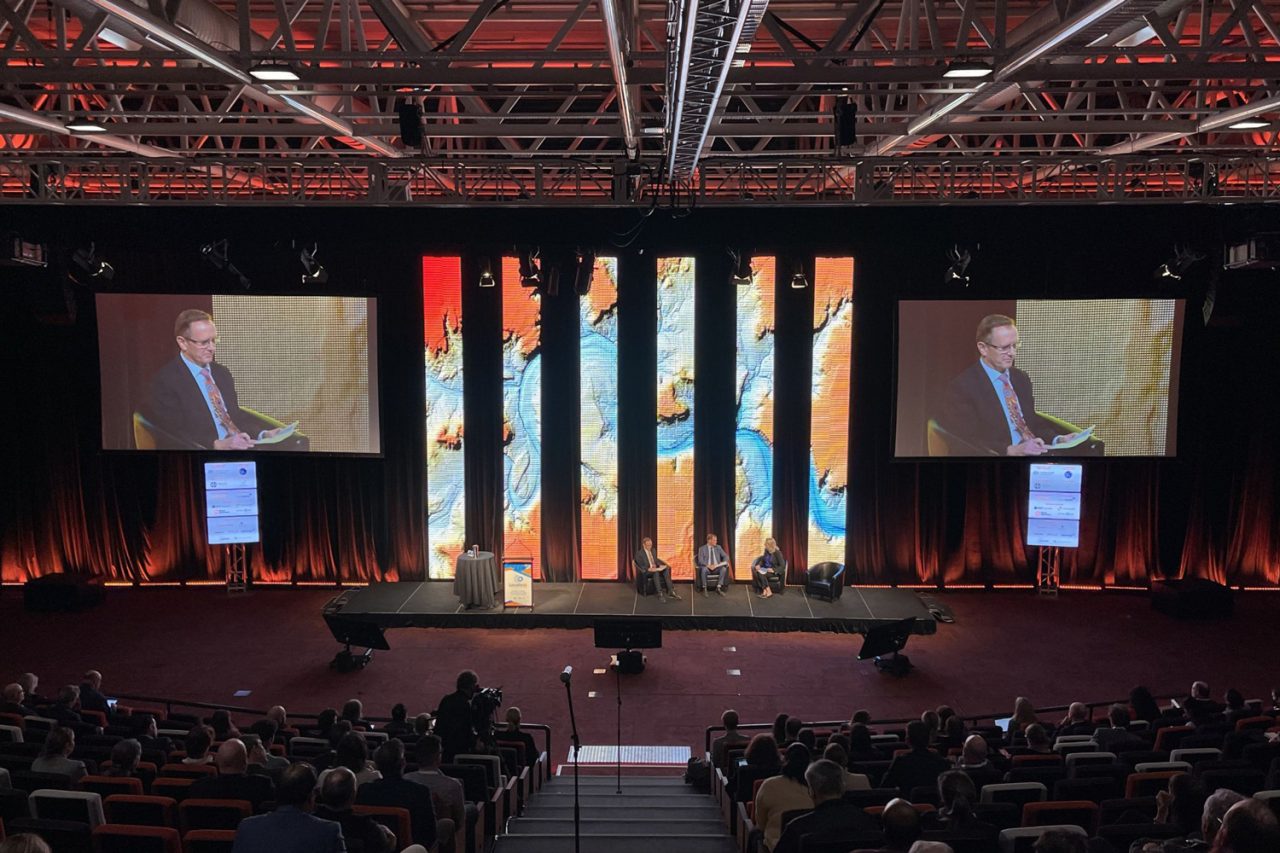 Six video columns between presentation screens on the Locate22 conference stage.