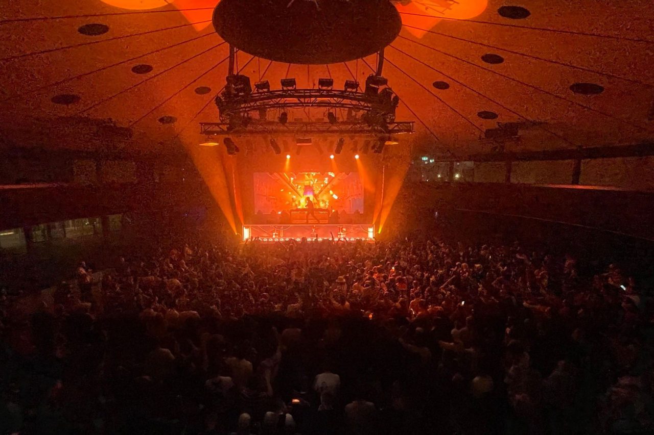 Wide view of the Roundhouse crowd facing an orange-lit stage.