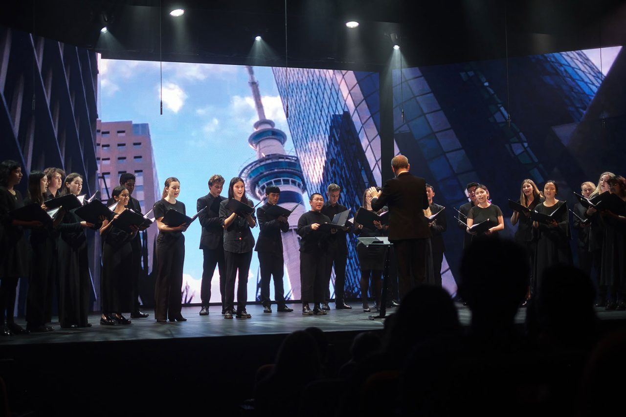Performers across the Taumata 2022 stage in front of a city video backdrop.