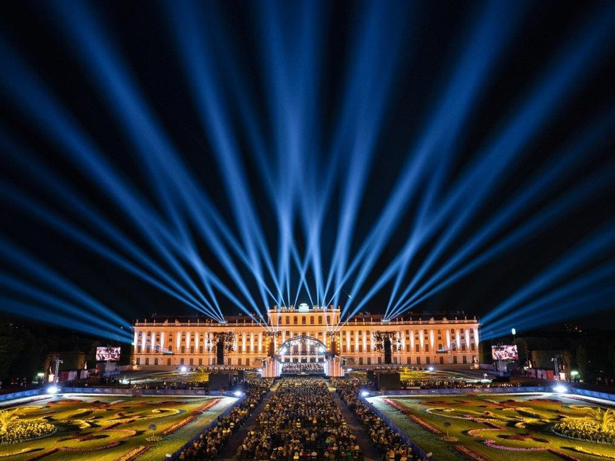 Blue beams fan above Schonbrunn Castle during the Vienna Philharmonic Summer Night Concert.