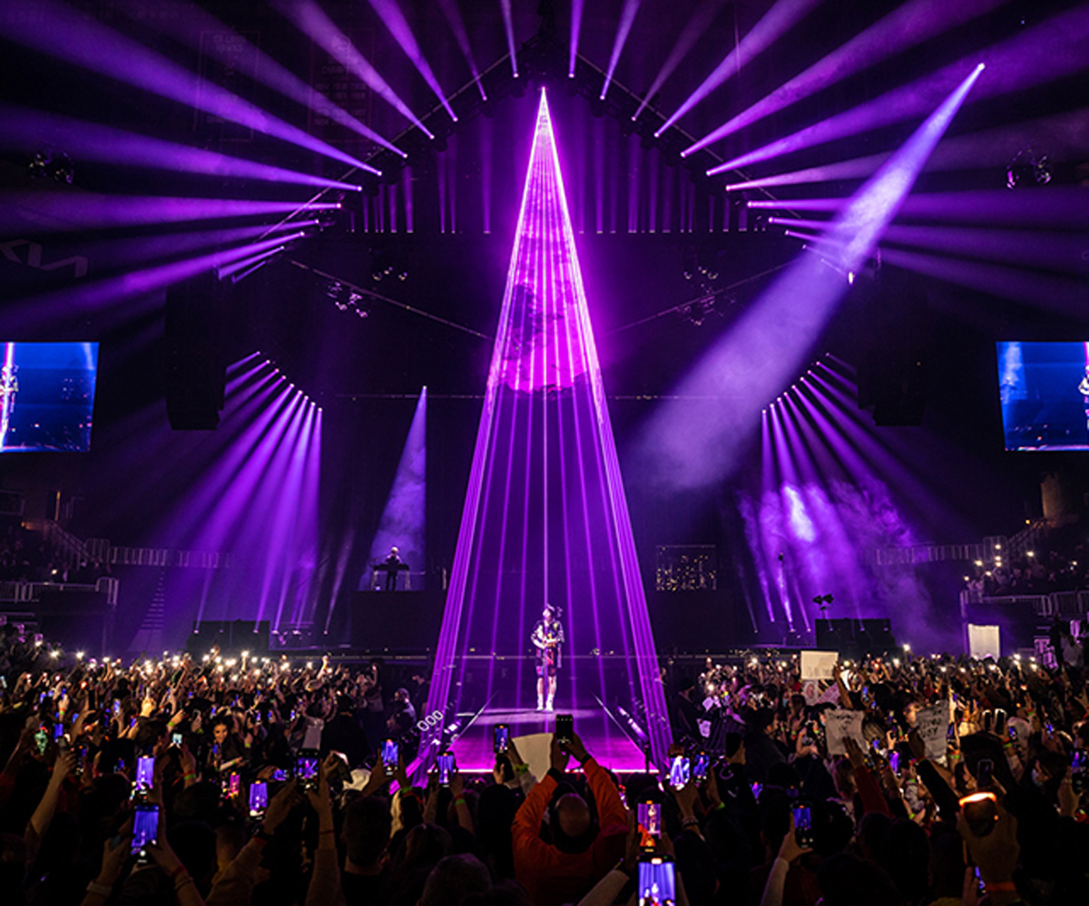 Purple beams form a tall triangular canopy above the Happier Than Ever stage.