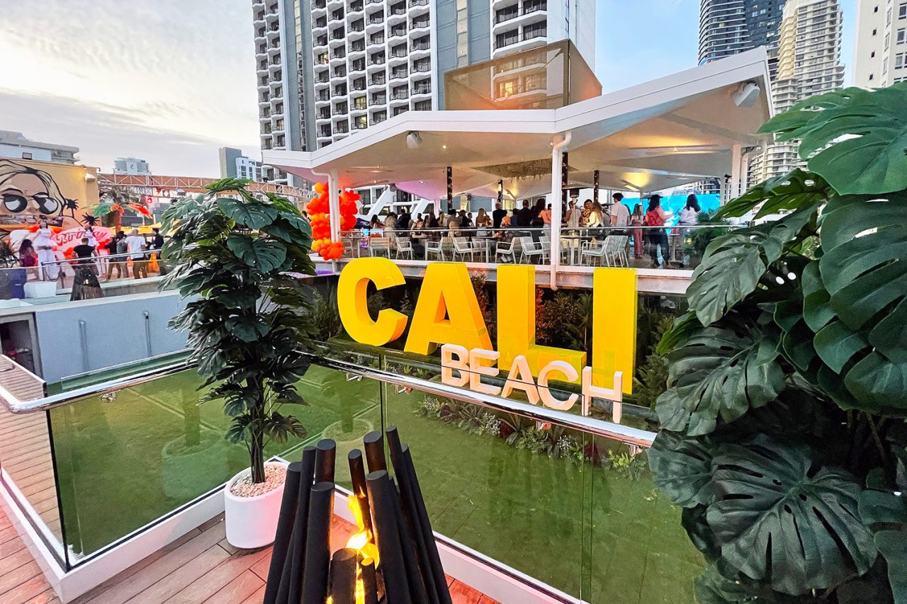 Rooftop party at Cali Beach behind the large yellow venue sign.