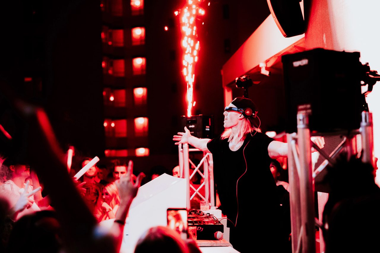 Red stage lighting and sparks above the crowd at Cali Beach's first birthday party.