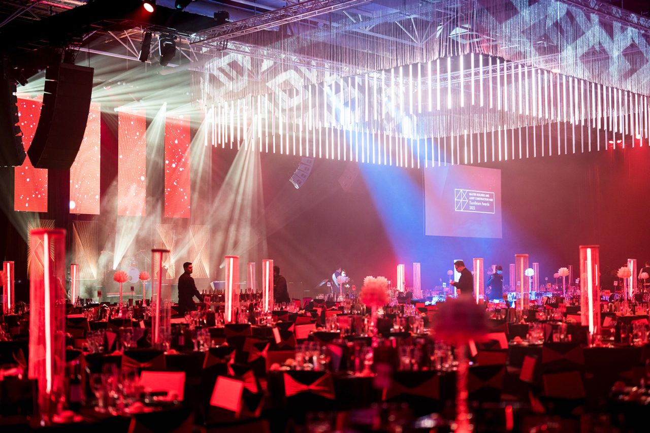 Red lighting over banquet tables beneath a suspended light installation at the 2022 Master Builders Australia awards.