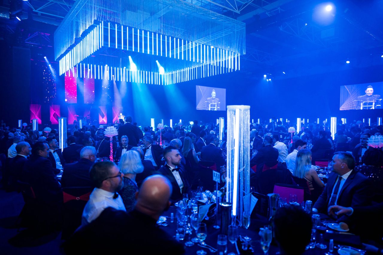 Guests beneath blue lighting and suspended tubes at the Master Builders awards.