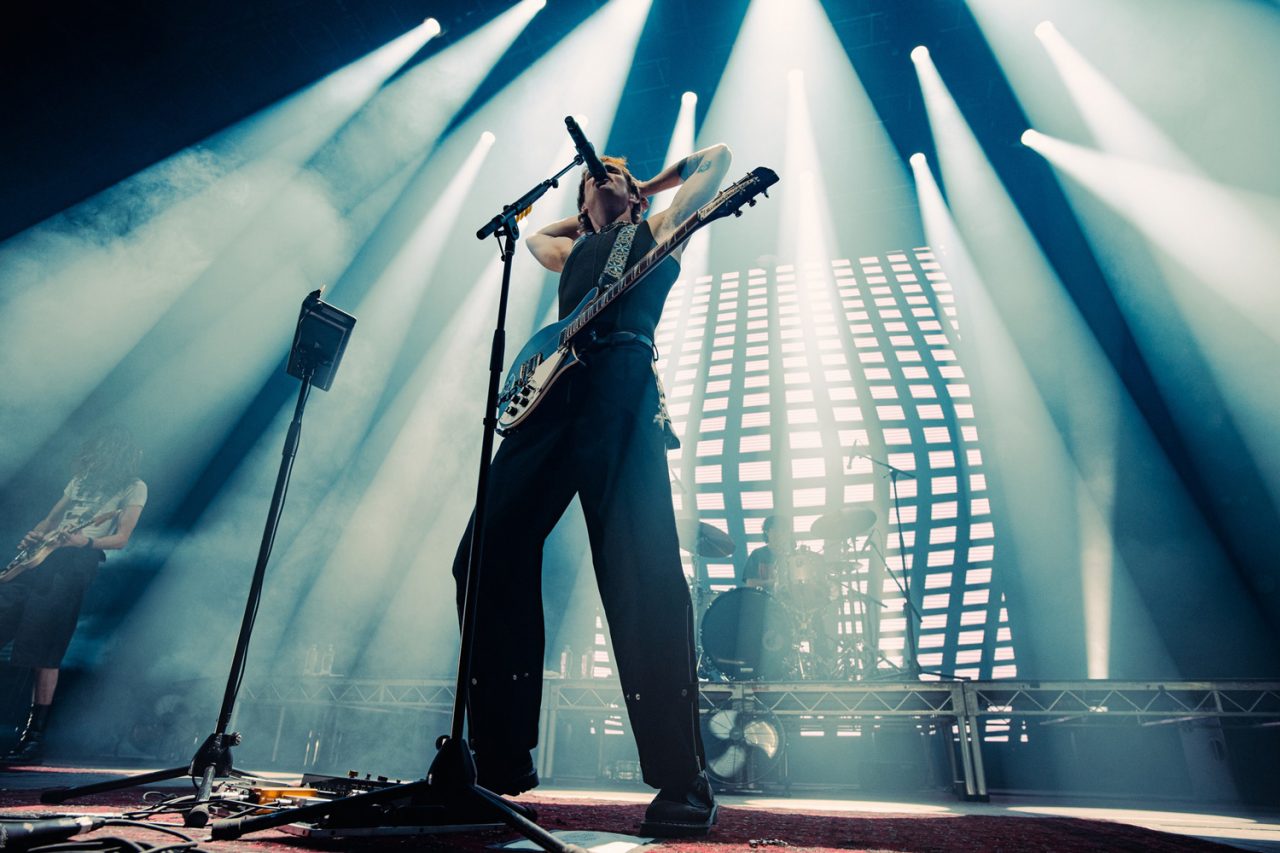 Guitarist beneath white beams and vertical lights on the Spacey Jane tour.
