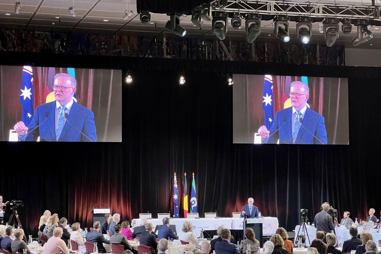 A speaker appears on two large screens above the Jobs and Skills Summit audience.