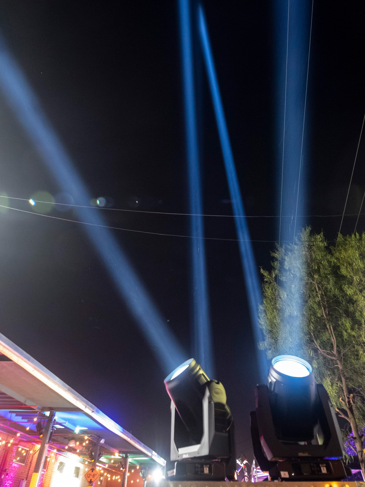 Proteus Excalibur fixtures project blue-white searchlight beams into the night sky.