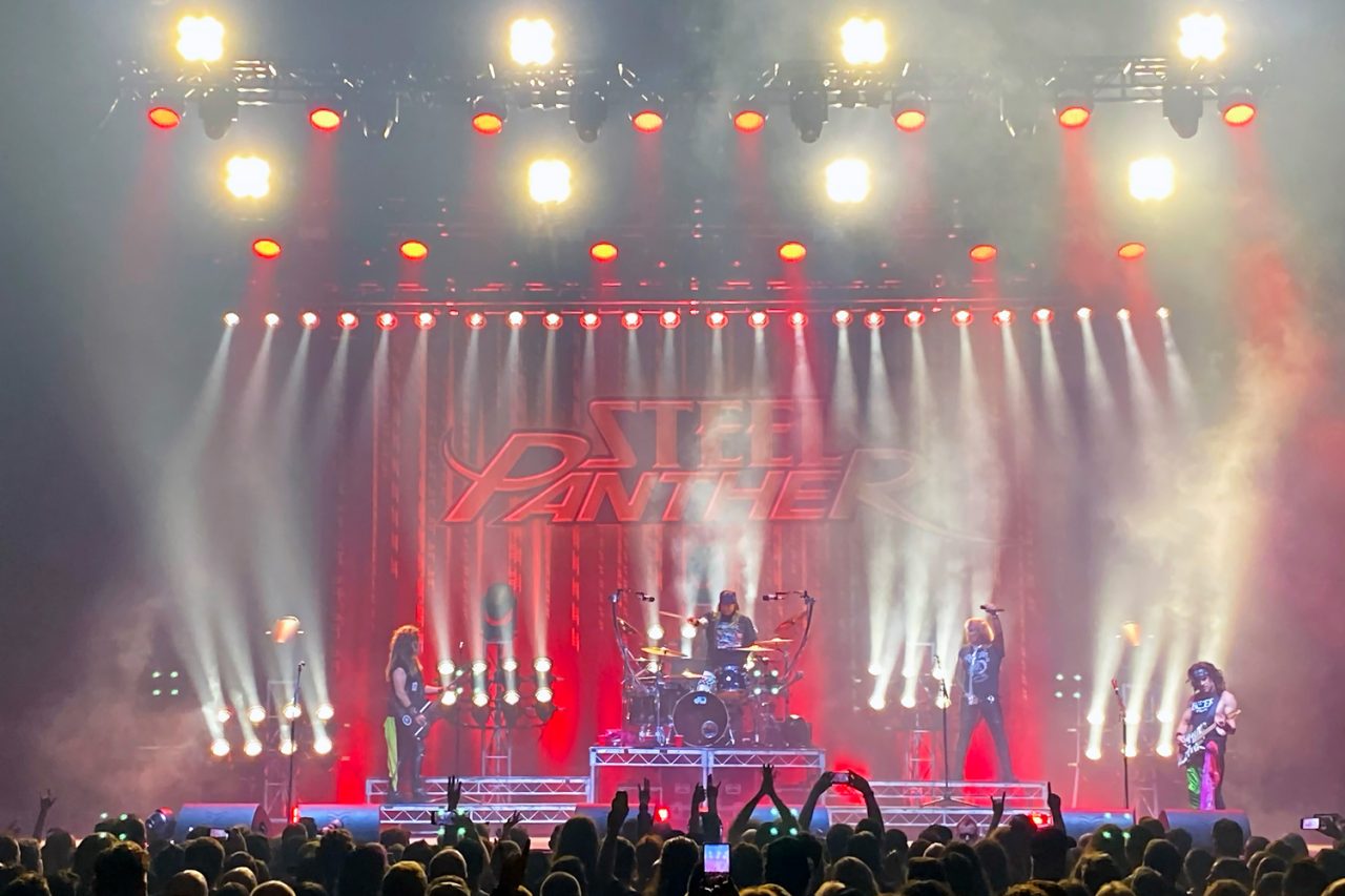 White beams across a red stage backdrop at a Steel Panther show.