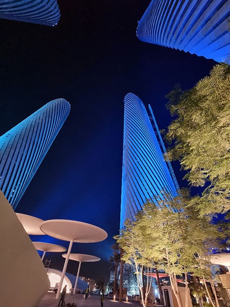 Looking upward between blue-lit Lusail Plaza Towers.