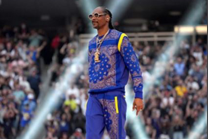 Vocalist in a blue outfit on a stadium halftime stage.