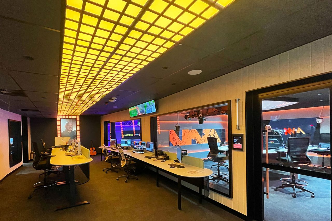 Yellow illuminated ceiling panels above workspaces outside Southern Cross Austereo studios.