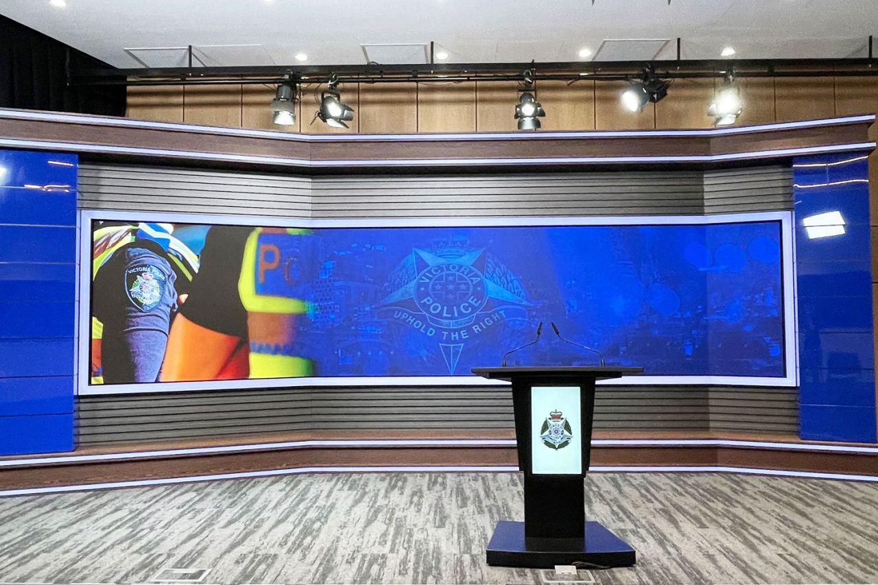 Wide video wall and presentation podium in the Victoria Police media centre.