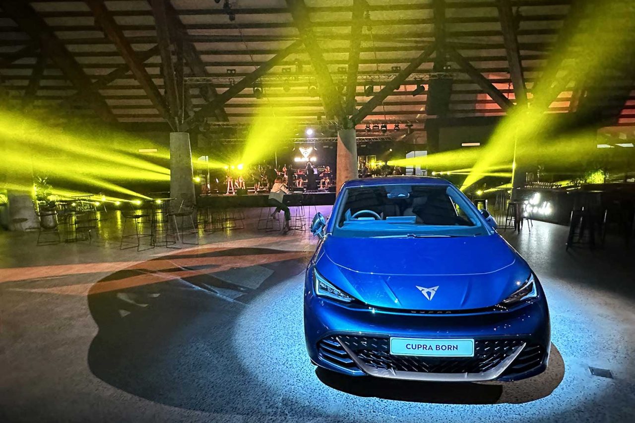 Front view of a blue Cupra Born beneath yellow lighting at the launch.